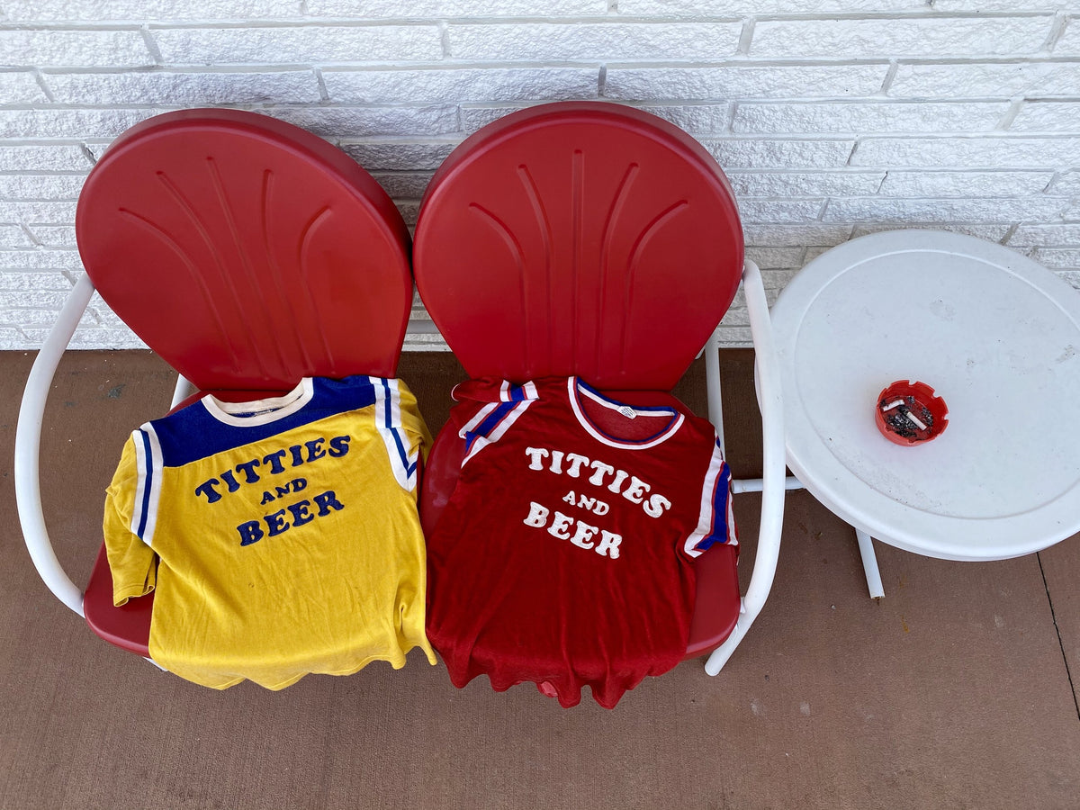 Two vintage Titties and Beer tees on red chairs