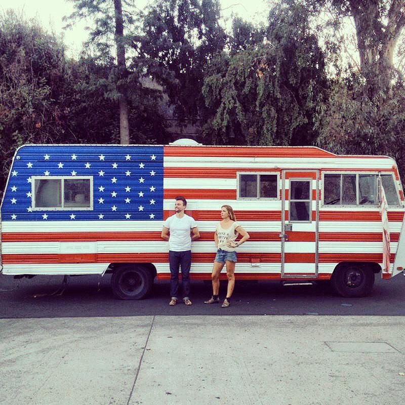 Jada and Jon in front of the stars-and-stripes RV